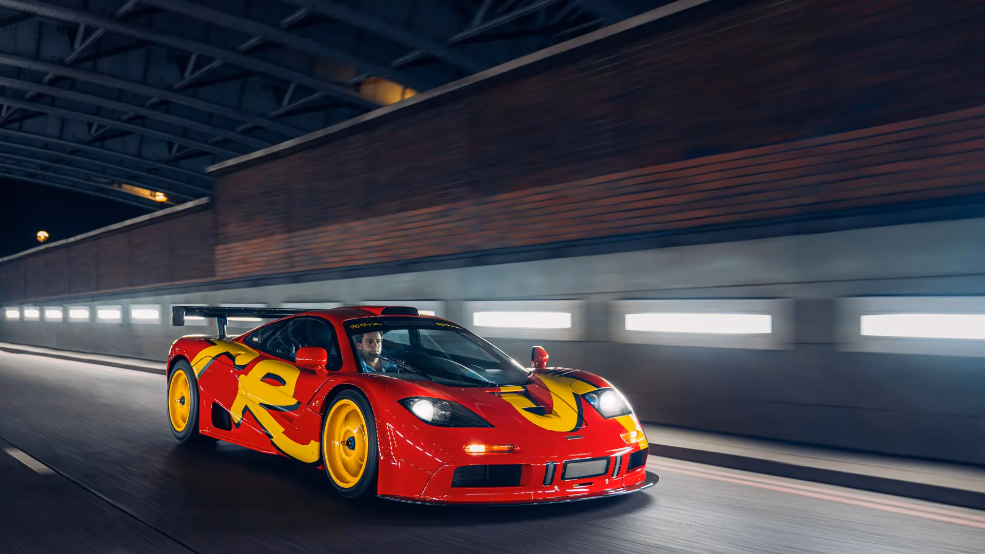1996 McLaren F1 GTR chassis 10R in its scarlet and yellow pop art factory livery with yellow wheels, photographed on the move